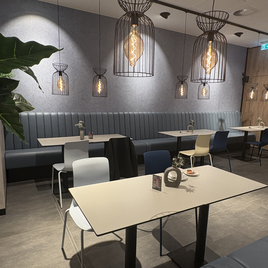 Modernes Café mit Schreibtischen, Stühlen und Beleuchtung.